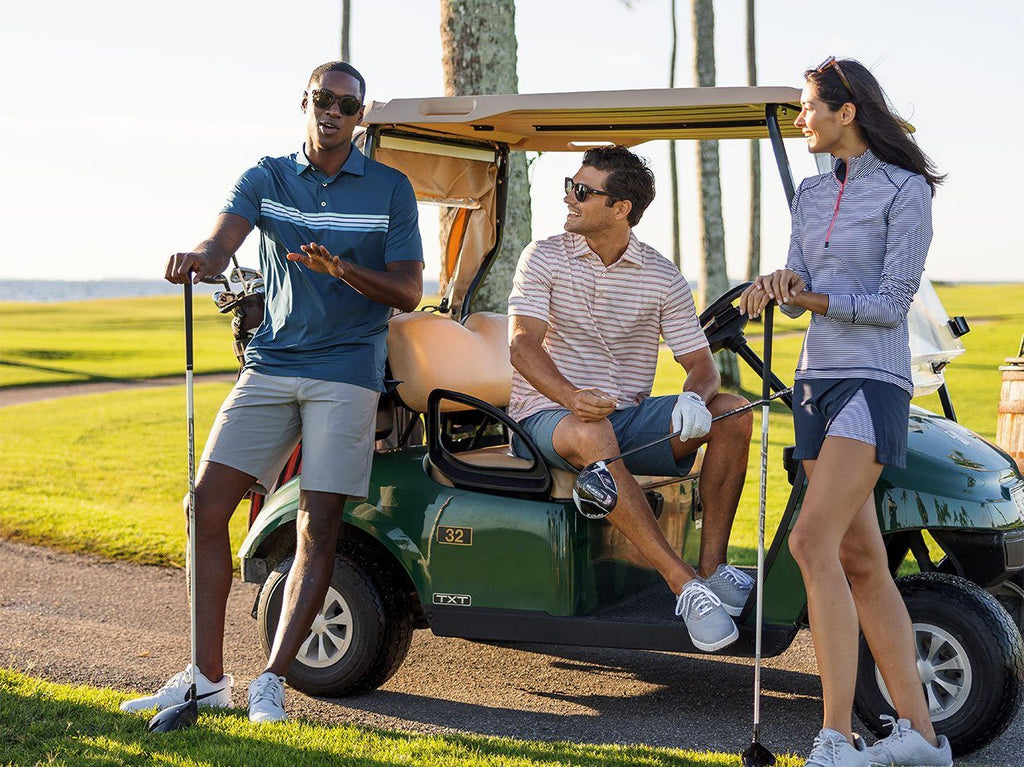 Two men and one women standing around a golf cart on a gold course.