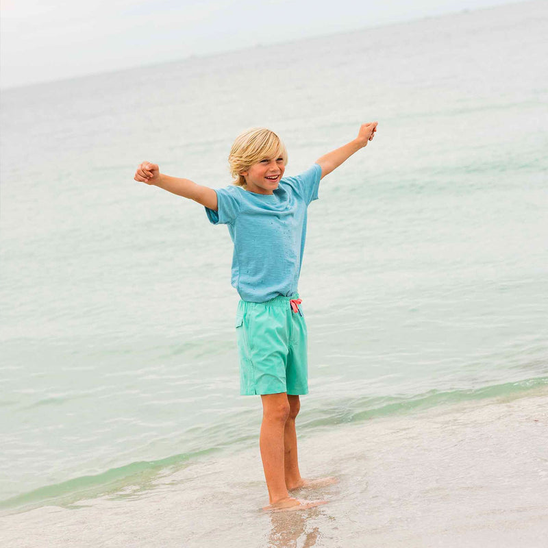 kids standing in front of ocean in solid swim trunk and t-shirt