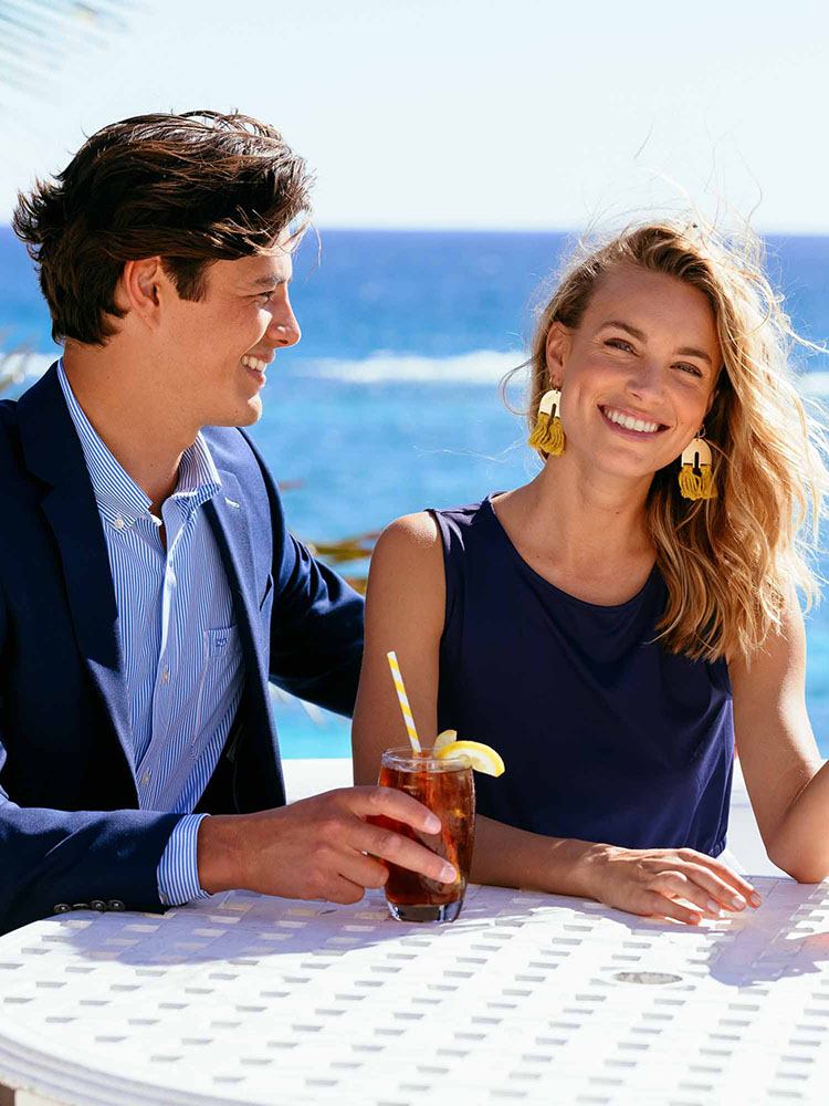 man and woman enjoying a drink at a table near the beach