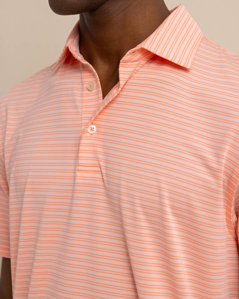 The detail view of the Southern Tide brrr eeze Beattie Stripe Performance Polo by Southern Tide - Apricot Blush Coral