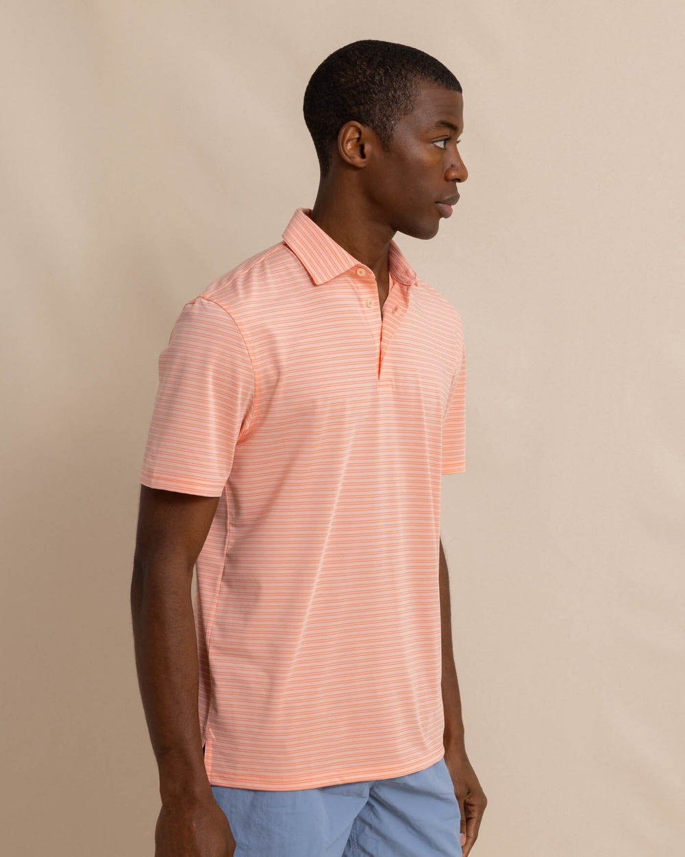 The front view of the Southern Tide brrr eeze Beattie Stripe Performance Polo by Southern Tide - Apricot Blush Coral