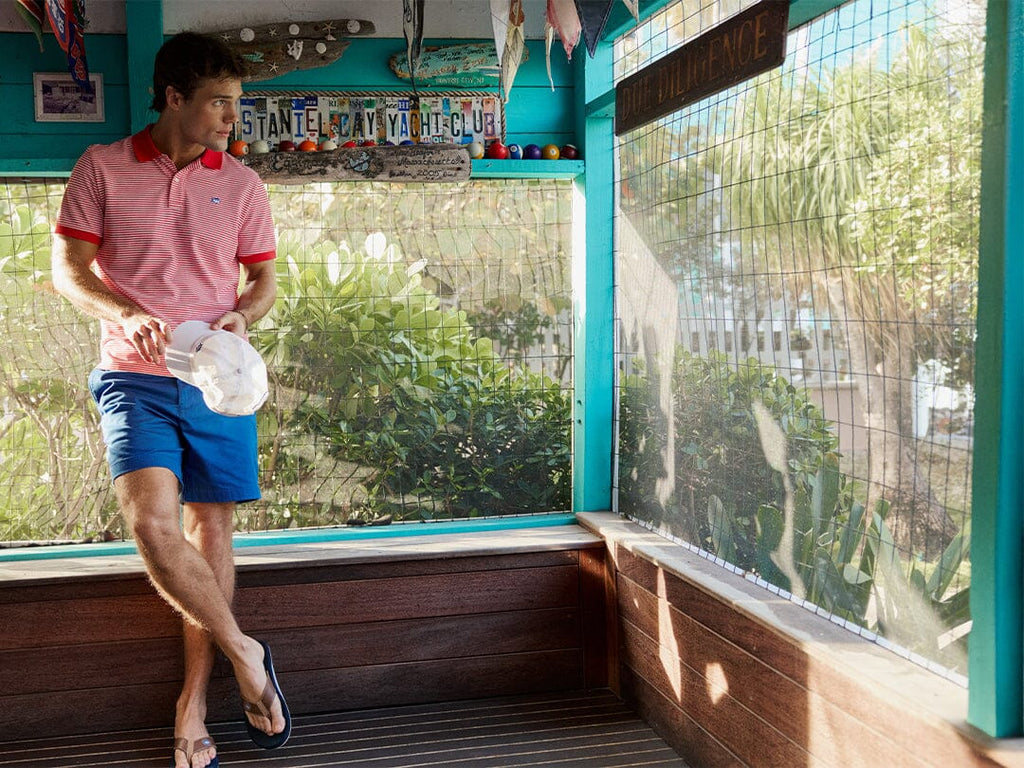 Man in red and white striped polo and blue shorts.
