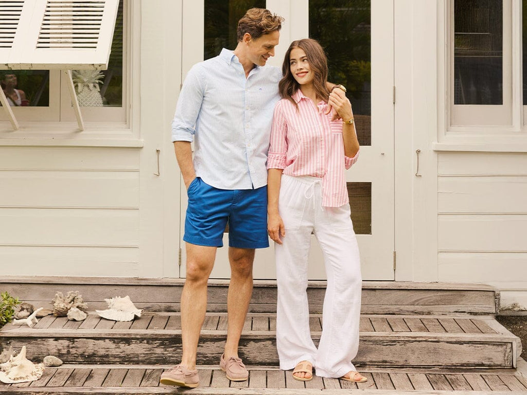 Girl standing by a palm tree wearing striped Moira romper.