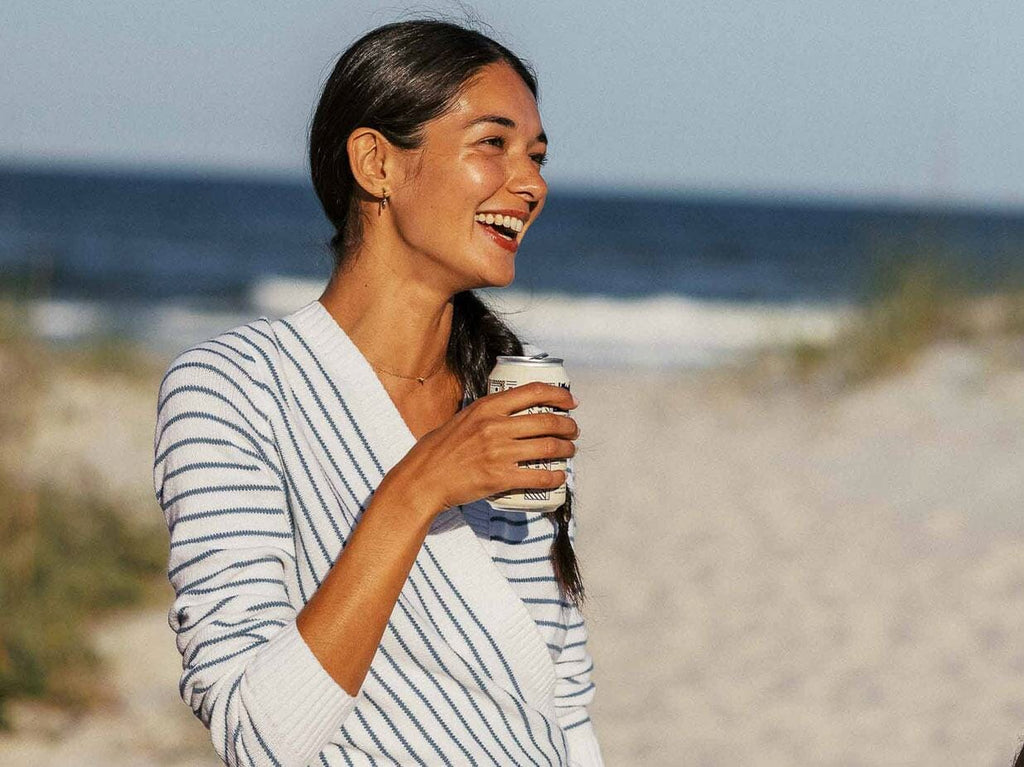 Woman wearing striped sweater drinking  beer.