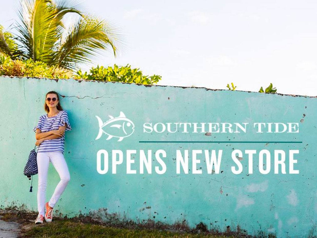 Woman leaning against blue concrete wall next to the Southern Tide logo.