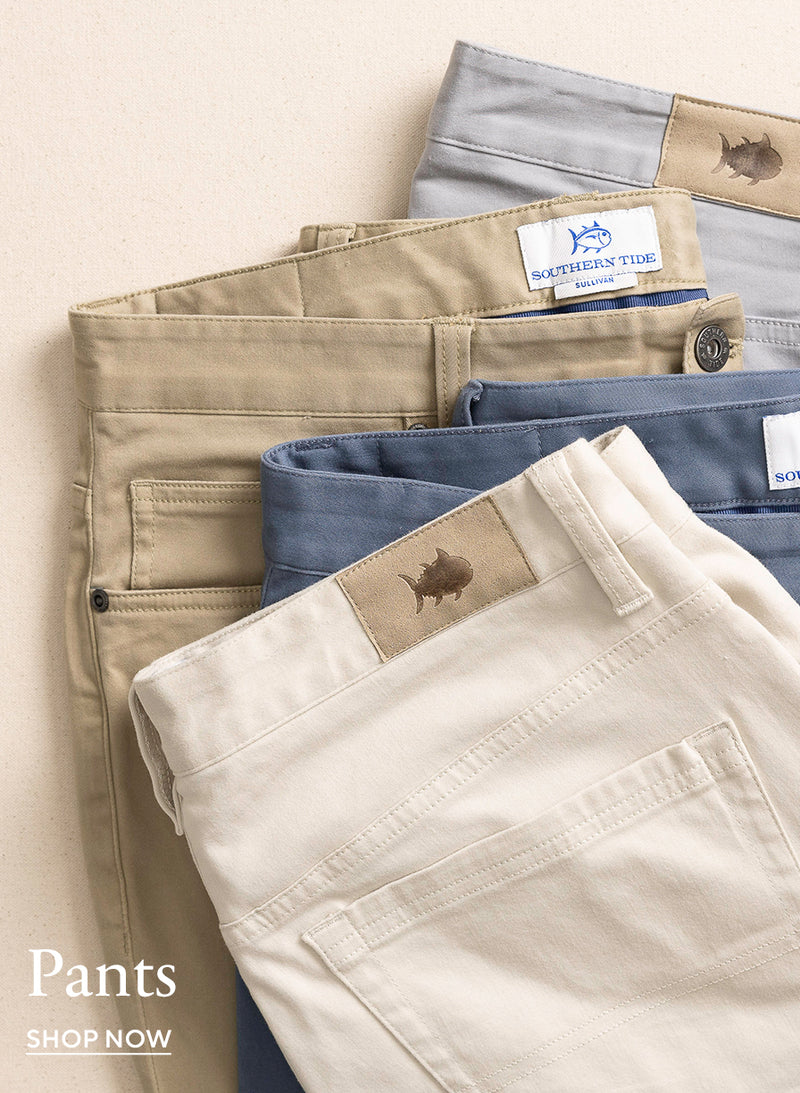 Multiple pairs of Southern Tide Sullivan Five Pocket Pants in assorted colors, stacked to display the five-pocket design and available color options.  Made with a flexible cotton blend for comfort and movement.