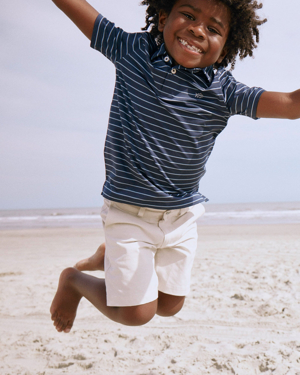 The lifestyle view of the Southern Tide Boys Driver Seaglass Stripe Polo by Southern Tide - Dress Blue