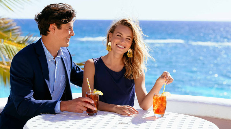 man and woman enjoying a drink at a table near the beach
