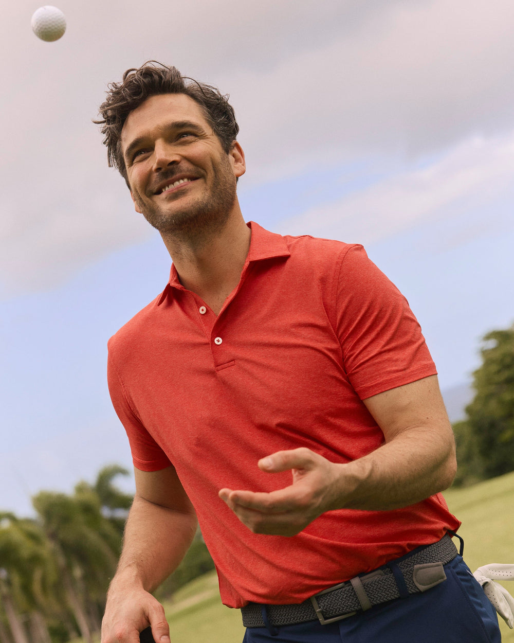 The lifestyle view of the Southern Tide brrr°®-eeze Heather Performance Polo Shirt by Southern Tide - Heather Poppy Red