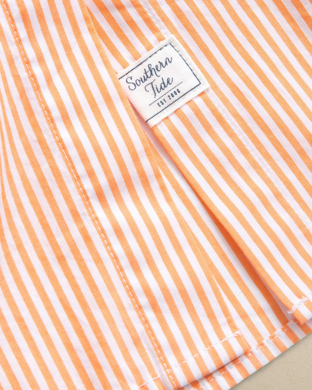 The detail laydown view of the Southern Tide Cam Stripe Poplin Dress by Southern Tide - Peach Parfait