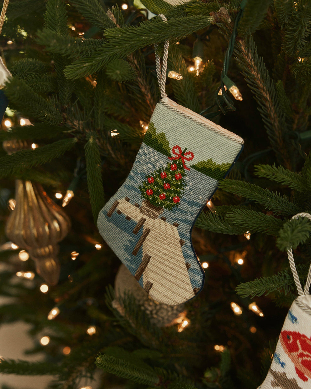The lifestyle view of the Southern Tide Festive Fir Needlepoint Stocking by Southern Tide - Blue