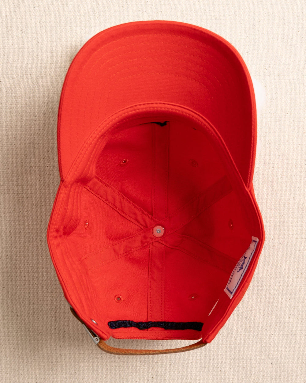 The under view of the Southern Tide Kids Uh Oh Sharks Leather Strap Hat by Southern Tide - Poppy Red