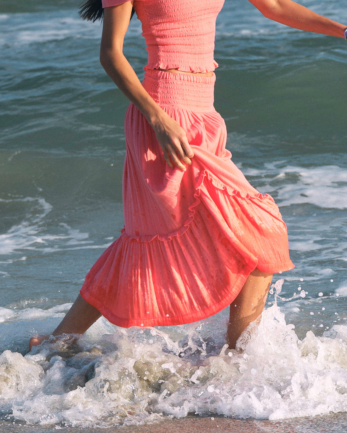 The lifestyle view of the Southern Tide Lydia Smocked Waist Midi Skirt by Southern Tide - Coral Beach