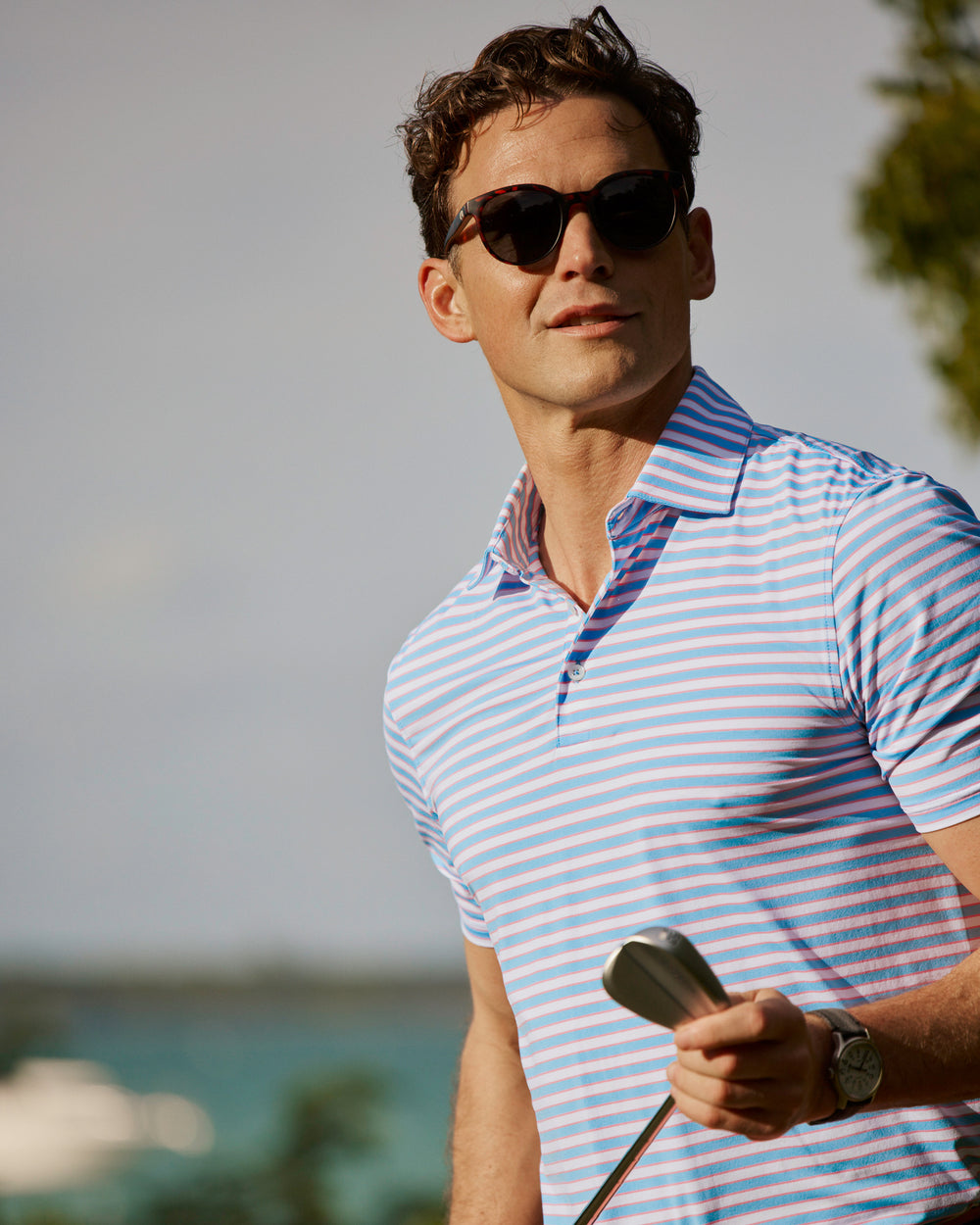 The lifestyle view of the Southern Tide Water Way Stripe Coastal Breeze® Performance Polo by Southern Tide - Ocean Channel