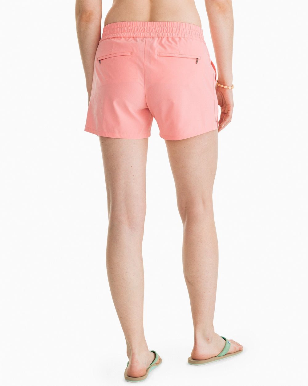 The back view of the Women's Pink Coastal Performance Solid Short by Southern Tide - Geranium Pink